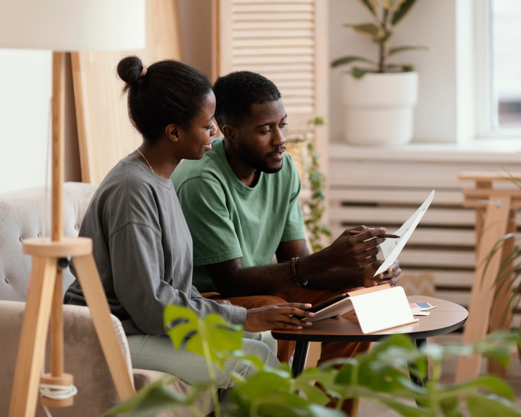 A Black couple reviewing plans together at home with a tablet and printed documents